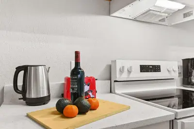 a bottle of wine and fruit on a cutting board on a kitchen counter at Restpool vibes, Nest tree-ish Retreat- NxtDisney in Kissimmee