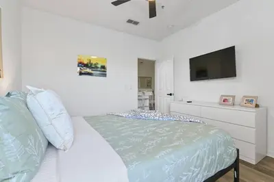 a white bedroom with a bed and a tv at Pause Discover something that nourishes your soul in Kissimmee