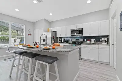 a kitchen with white cabinets and a large island with bar stools at Finest renovated w Pool, Game rm, 4 Mi to Disney in Kissimmee