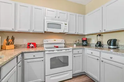 a kitchen with white cabinets and white appliances at SPECTACULAR CONDO only 4 Miles to Disney! in Kissimmee