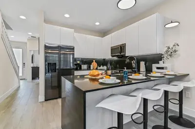 a kitchen with white cabinets and a counter with stools at Look Out over Nature - Unique FRESH Corner Home in Orlando