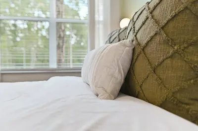 a bed with a pillow next to a window at Discover paradise - NEW! Pool House Next to Disney in Orlando
