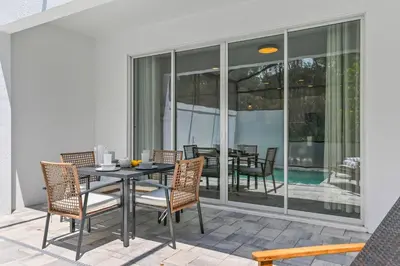 a patio with a table and chairs and a pool at Oasis NEW Townhome Splash Pool Nature-Infused in Orlando