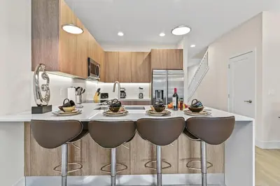 a kitchen with a bar with stools in the middle at Discover Your Escape - NEW house wPrivate Pool in Orlando