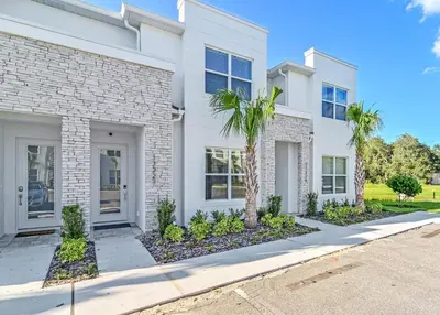 a white brick house with a palm tree in front of it at Happiness is a destination ! - NEW house with pool in Orlando