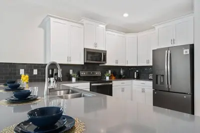a kitchen with white cabinets and a stainless steel refrigerator at Casa 9Q no Storey Lake c/ Piscina Cinema e Games in Kissimmee