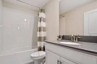 a white bathroom with a toilet and a sink at Casa 9Q no Storey Lake c/ Piscina Cinema e Games in Kissimmee