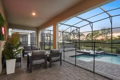 a living room with a patio and a swimming pool at Casa 9Q no Storey Lake c/ Piscina Cinema e Games in Kissimmee