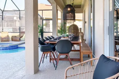a dining table and chairs on a patio with a pool at New Modern STAR WARS Villa Only 3 Miles 2 Disney w VR's in Kissimmee