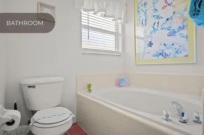 a bathroom with a tub and a toilet and a window at Cozy 3BR Family Home Minutes from Disney in Kissimmee