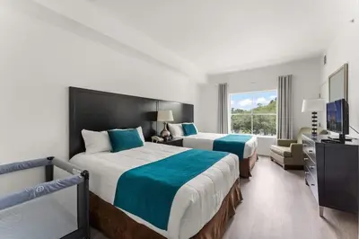 a hotel room with two beds and a television at Apto c/ Vista Piscina – Perto da Disney 1Q in Orlando