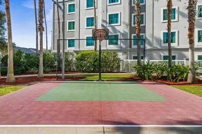 a basketball hoop in front of a building with palm trees at Apto c/ Vista Piscina – Perto da Disney 1Q in Orlando