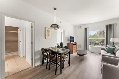 a dining room and living room with a table and chairs at Apto c/ Vista Piscina – Perto da Disney 1Q in Orlando