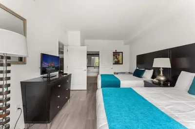 a hotel room with two beds and a flat screen tv at Apto c/ Vista Piscina – Perto da Disney 1Q in Orlando