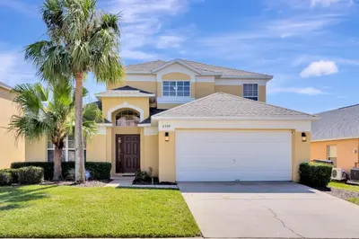 a large yellow house with a white garage at Spacious 5-Bedroom 4-Bath Pool & Spa Villa in Emerald Island Resort in Kissimmee