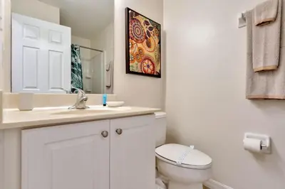 a white bathroom with a toilet and a sink at Spacious 5-Bedroom 4-Bath Pool & Spa Villa in Emerald Island Resort in Kissimmee