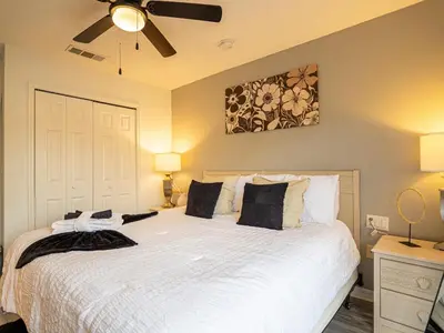 a bedroom with a large white bed with a ceiling fan at The Enchanted luxe Townhome in Kissimmee