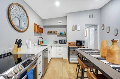 a kitchen with white cabinets and a large clock on the wall at Fireplace and Lake View Just 10 Minutes to Downtown Near Parks in Orlando