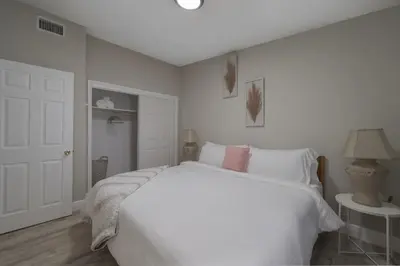 a white bedroom with a large bed and a lamp at Cozy 2 bedroom home in Orlando in Orlando