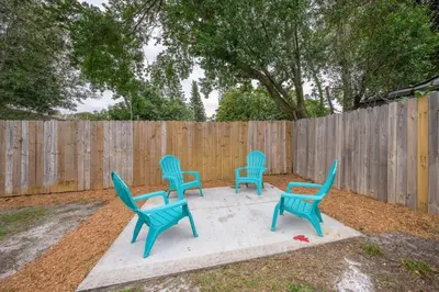 four blue chairs sitting on a concrete slab in front of a fence at Comfortable 1 bedroom home in Orlando