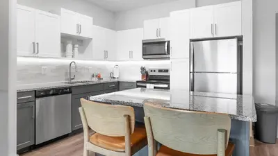 a kitchen with white cabinets and a counter with two chairs at Landing Chic 1BD Gym Pool in Sanford