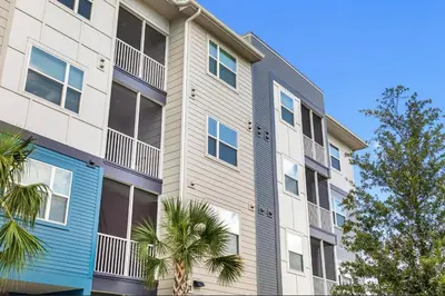 an apartment building with blue windows and palm trees at Landing Chic 1BD Gym Pool in Sanford