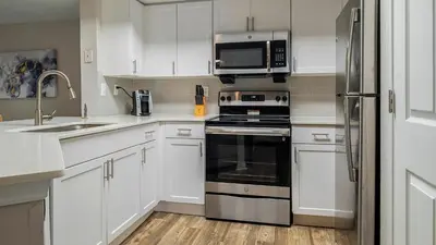 a kitchen with white cabinets and a stove and microwave at Landing Chic 1BD Gym in Orlando