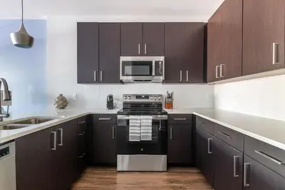 a kitchen with brown cabinets and a stove top oven at Landing Beautiful 2BD in Kissimmee in Kissimmee