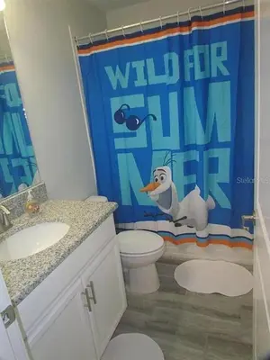 a bathroom with a toilet and a shower curtain at 4715 SH - Storey Lake Hideaway 6BR Mansion Private Pool in Kissimmee