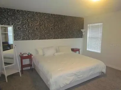a bedroom with a bed and a wall with a wallpaper at 4715 SH - Storey Lake Hideaway 6BR Mansion Private Pool in Kissimmee