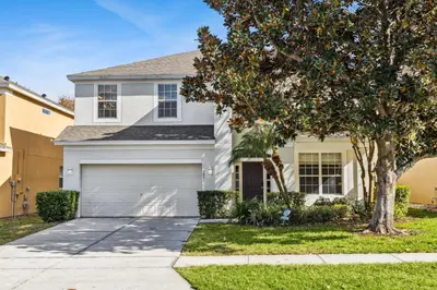 a white house with a tree and a garage at Arcade and Pool Villa, 4 km to Disney in Orlando