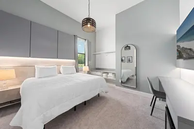a white bedroom with a bed and a desk at Brand New Modern State of the Art Home! Sleeps 31 in Kissimmee