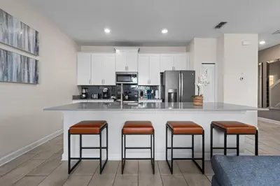 a kitchen with a large island with bar stools at Chic Resort Getaway – 15 Min to Disney in Kissimmee