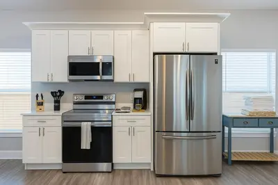 a kitchen with white cabinets and a stainless steel refrigerator at Disney-Area 4BR | Pool + Patio in Kissimmee