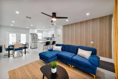 a living room with a blue couch and a kitchen at Downtown Home with Basketball, Firepit and Just 20 Miles to Disney in Saint Cloud