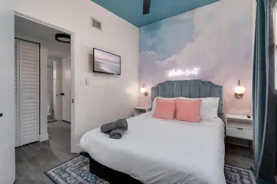a bedroom with a large white bed with pink pillows at 10 Minutes to Downtown with Jacuzzi, Pool Table, Ping Pong, and BBQ in Orlando
