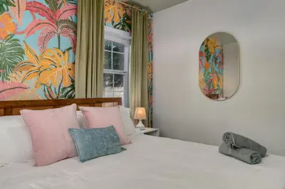 a bedroom with a bed with pink pillows and a mirror at 10 Minutes to Downtown with Jacuzzi, Pool Table, Ping Pong, and BBQ in Orlando