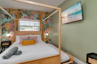 a bedroom with a four poster bed with white sheets at Cozy Orlando Studio with Jacuzzi, Fire Pit, and BBQ in Orlando
