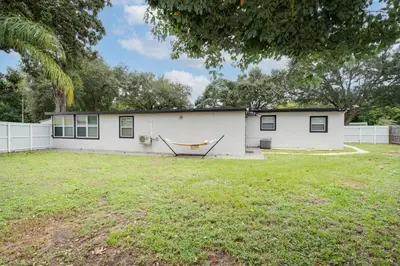 a white house with a hammock in a yard at Stylish 2BR Home Near Disney and Universal Orlando in Orlando