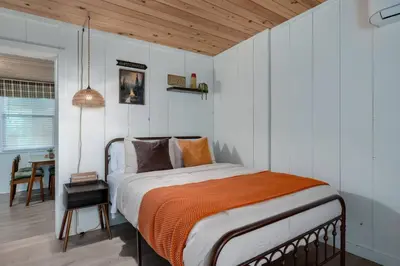 a bedroom with a bed with an orange blanket at Modern Downtown Orlando Studio in a Prime Location in Orlando