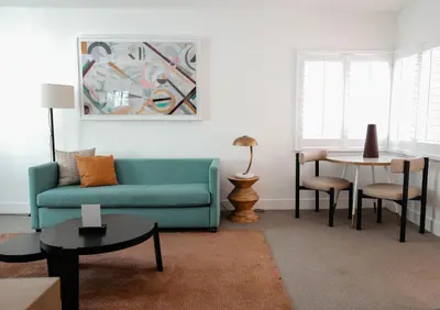 a living room with a blue couch and a table at Suites by The Wellborn in Orlando