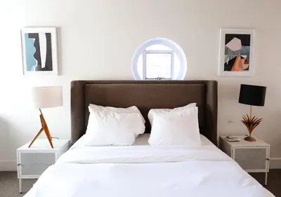 a bedroom with a white bed with white pillows at Suites by The Wellborn in Orlando