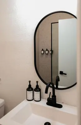 a bathroom sink with a mirror and two bottles on it at Suites by The Wellborn in Orlando
