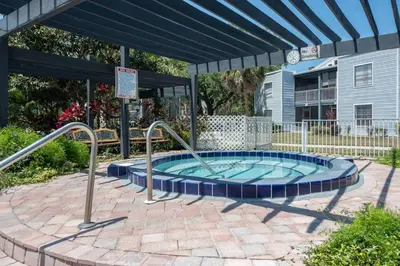 a hot tub in a patio with an umbrella at Condo with Pool, Gym, Golf, Jacuzzi and Game Areas in Orlando