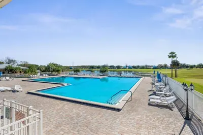 a large swimming pool with chairs and a fence at Cozy Apt with Pool, Hot Tub, Golf, Near Downtown in Orlando