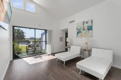 a living room with white furniture and a large window at Cozy Apt with Pool, Hot Tub, Golf, Near Downtown in Orlando