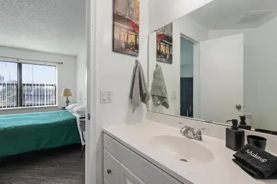 a bathroom with a sink and a mirror and a bed at Cozy Apt with Pool, Hot Tub, Golf, Near Downtown in Orlando