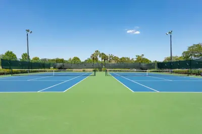 a tennis court with two tennis courts at Cozy Golf Condo with 3 Pools, Gym and Just 15 Minutes to Airport in Orlando