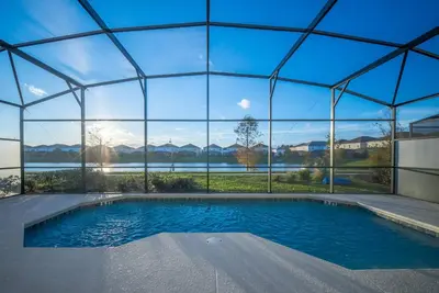 a swimming pool in a glass house with a view of the water at 2026 NEW Home 8 Bedrooms At Bella Vida in Kissimmee