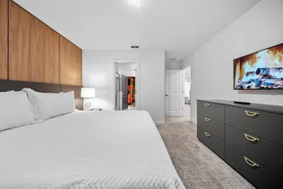 a bedroom with a white bed and a flat screen tv at Brand NEW Home 09 BedroomsPoolGame Room in Kissimmee